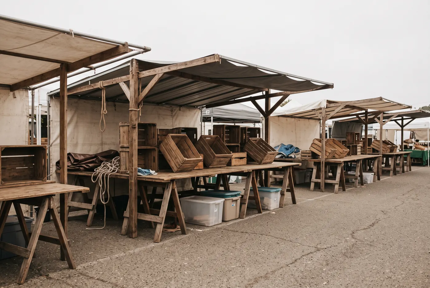 Empty farmers market stalls with wooden crates stacked on trestle tables.