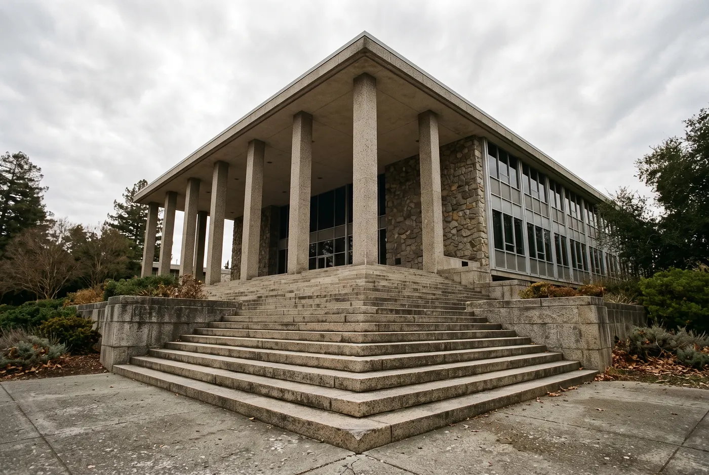 The stone steps and columns of a mid-century civic building seen from below.